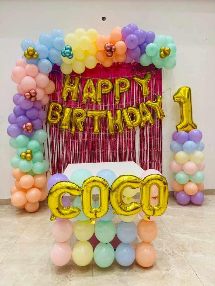 Premium Pastel Theme Birthday Decoration featuring a pastel balloon backdrop, shimmer curtain, custom name foil letters, Happy Birthday foil balloons, age number balloon, balloon pillars, and Cocomelon theme setup. Perfect for 1st birthday, kids birthday, and home birthday celebrations in Delhi NCR. Balloon colours can be customized as per your choice.