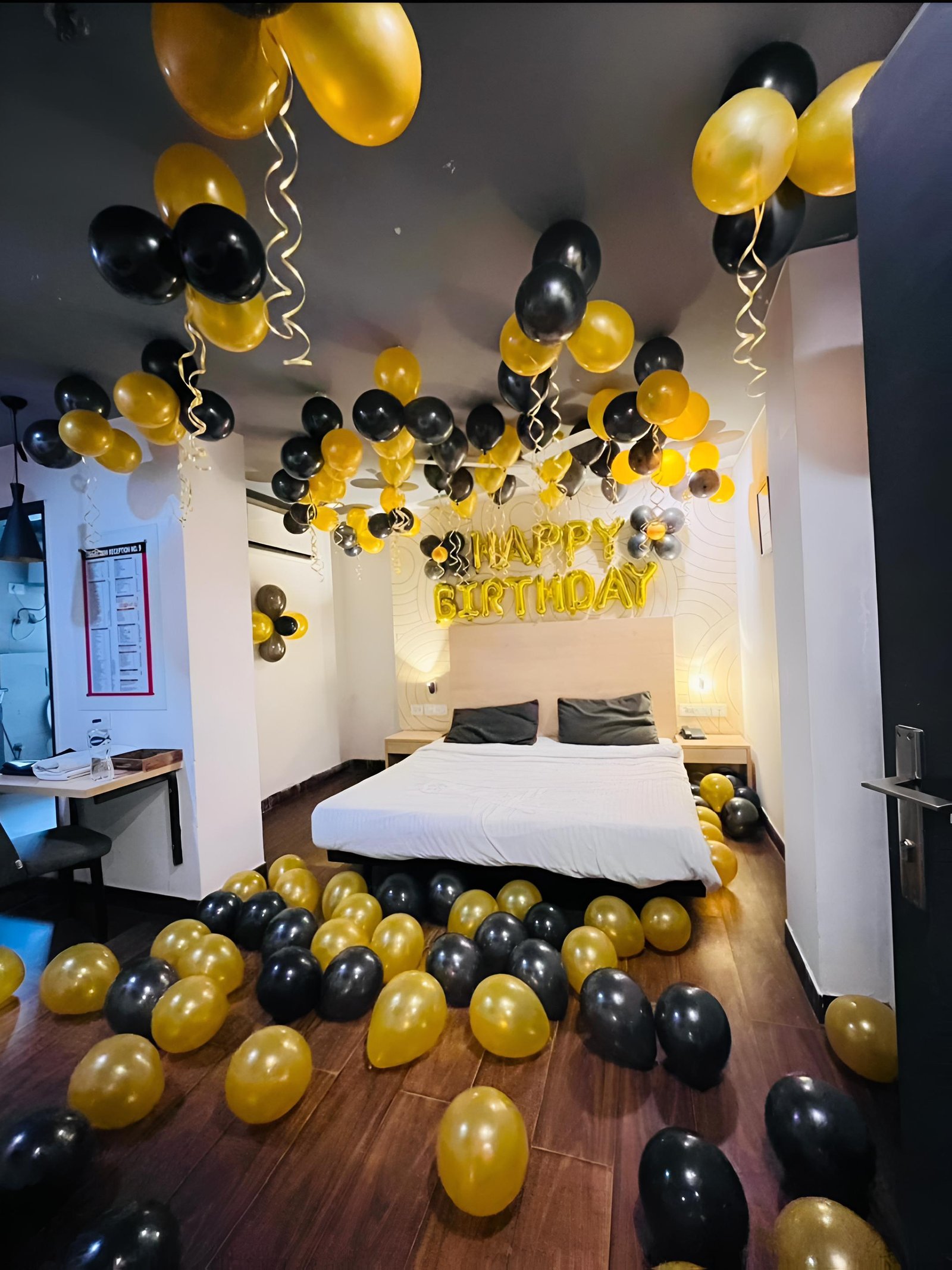 Premium surprise birthday room decoration featuring black and golden balloons, ceiling balloon decoration, hanging ribbons, Happy Birthday foil letters and elegant floor balloon arrangements. This stylish birthday party decoration in Delhi, Uttam Nagar is perfect for surprise celebrations and special occasions. Looking for balloon decoration near me or birthday party decoration in Delhi? Our decoration can be fully customized according to your choice of balloon colours, theme, name and age number.